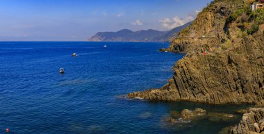 İtalya 'nın Cinque Terre kentindeki Riomaggiore kasabasından gelen su üzerindeki kayık ve kayalıklarla Akdeniz' e gündüz panoramik manzara