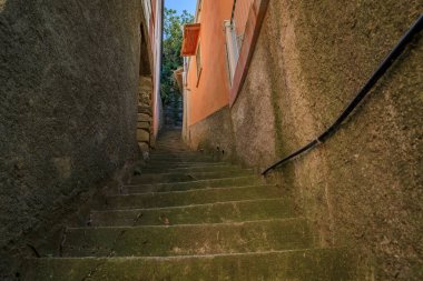 İtalya 'nın Akdeniz kenti Cinque Terre' de eski bir kasaba caddesi olan Riomaggiore 'daki geleneksel eski teras evleri arasındaki dik merdivenler.