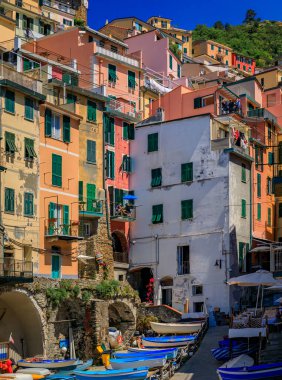 Bir yamaçtaki geleneksel renkli evler ve İtalya 'nın Akdeniz kıyısındaki Cinque Terre' deki eski Riomaggiore kasabasında balıkçı tekneleri.