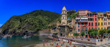Vernazza, İtalya - 01 Haziran 2022: Geleneksel renkli evler ve Cinque Terre 'deki Akdeniz Sahili kıyısındaki Santa Margherita di Antiochia Kilisesi