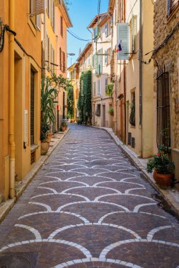 Ornate mosaic street pavement between traditional old houses near the covered provencal farmers market in old town or Vieil Antibes, South of France