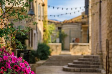Fransa 'nın güneyindeki Saint Paul de Vence, Fransız Rivierası' nda çiçeklerin arasından görülen geleneksel taş evler.