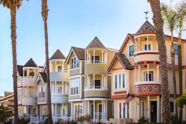 Huntington Beach, Orange County, California 'da sörfle ünlü palmiye ağaçlarıyla dolu bir caddedeki eski Viktorya dönemi evleri süsleyin.