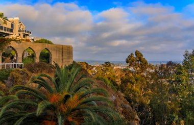 Lüks evlerin üzerinde gün batımı, Dana Point limanında güzel bir palmiye ağacı ve botlar, Güney Kaliforniya 'da Orange County, bulutlu bir günde, panoramik manzara
