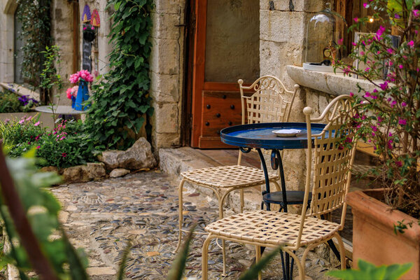 A small metal table and chairs at an outdoor restaurant in the medieval town of Saint Paul de Vence, French Riviera, South of France