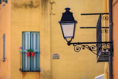 Resimli eski sokak lambası, arka planda panjurları olan renkli geleneksel evler eski Fransız Riviera, Fransa 'nın güneyindeki Menton kasabasında.