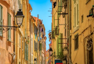 Resimli eski sokak lambası, arka planda panjurları olan renkli geleneksel evler eski Fransız Riviera, Fransa 'nın güneyindeki Menton kasabasında.