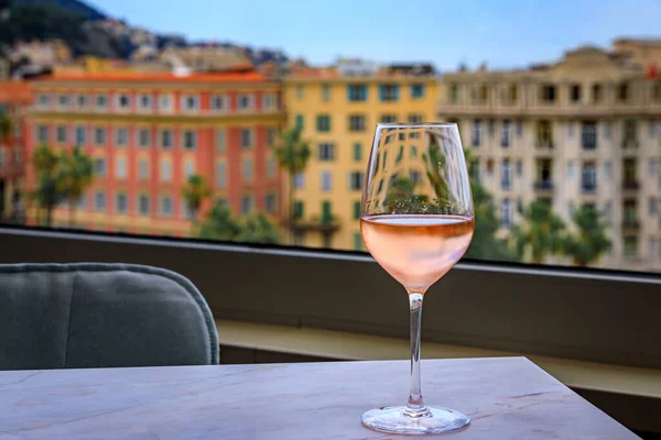 Glass of rose provencal wine at an outdoor rooftop bar above the Old Town Vieille Ville with blurred buildings in the background, Nice South of France