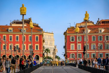 Nice, Fransa - 29 Mayıs 2023: Turistler Massena Meydanı 'nı renkli binalar ve Soleil Çeşmesi ile büyük ticari ve kültürel yapılarla ziyaret ettiler