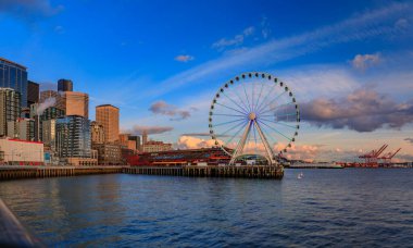 Panoramik şehir merkezi kıyı şeridi gökdelenleri ve Büyük Tekerlek manzarası Seattle, Washington, ABD 'de gün batımında Puget Sound.