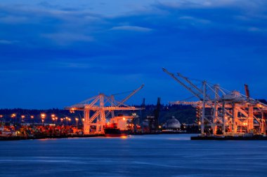 Limandaki vinçler, Puget Sound ve Seattle, Washington, ABD 'de günbatımında ışıkları olan Seattle rıhtımının ufuk çizgisi.