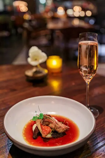 美国华盛顿州西雅图 一家精致的餐厅 桌上放着一杯闪闪发光的玫瑰香槟酒 上面点缀着蜡烛和郁金香花 免版税图库图片