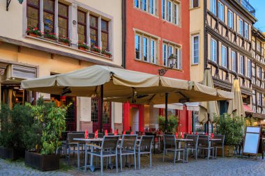 Gün batımında Fransa 'nın Strasbourg kentindeki geleneksel bir yarı keresteli evdeki Alsas şaraphanesinde kareli masa örtüsü olan masalar.