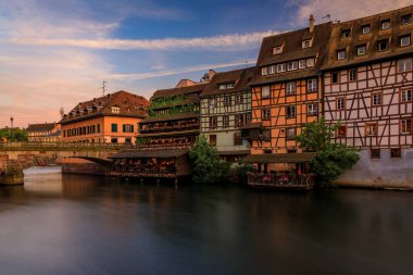 Günbatımında Fransa 'nın Strazburg, Alsace bölgesindeki Petite France bölgesinde çiçek açan çiçeklerle süslü geleneksel yarı ahşap evler.