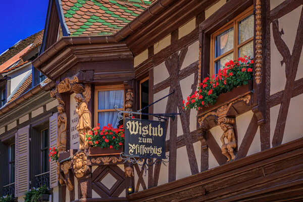 Ribeauville, France - June 2, 2023: Pfifferhus, Alsatian winstub restaurant in a half timbered house with flowers in a village on Alsatian Wine Route