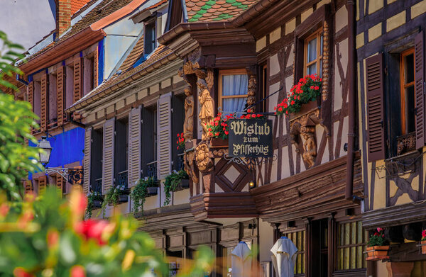 Ribeauville, France - June 2, 2023: Pfifferhus, Alsatian winstub restaurant in a half timbered house with flowers in a village on Alsatian Wine Route