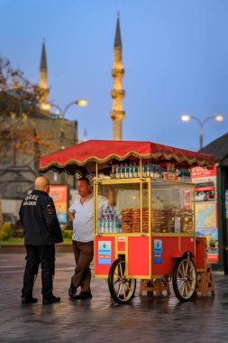 İstanbul, Türkiye - 8 Kasım 2023: Gündoğumunda Eminonu 'da geleneksel Türk sokak yemekleri olan simit arabasındaki müşteriler