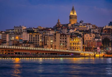 Türkiye 'nin İstanbul kentindeki Galata Kulesi' nin mavi saatinde Galata Köprüsü yakınlarındaki İstanbul Boğazı 'ndaki Karaköy bölgesinin gün doğumu manzarası