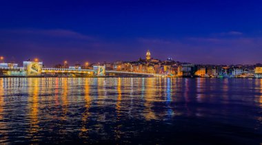 Türkiye 'nin İstanbul kentindeki Galata Kulesi' nin mavi saatinde Galata Köprüsü yakınlarındaki İstanbul Boğazı 'ndaki Karaköy bölgesinin gün doğumu manzarası