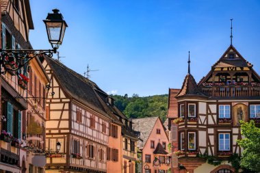 Ornate traditional half timbered houses with blooming flowers in a popular village on the Alsatian Wine Route in Kaysersberg Vignoble, France clipart