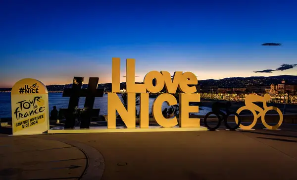 Stock image Nice, France - May 26, 2024: I Love Nice and Tour de France sign on Promenade des Anglais, nighttime cityscape and the Bay of Angels or Baie des Anges