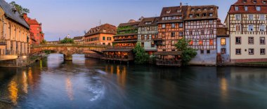 Günbatımında Fransa 'nın Strazburg, Alsace bölgesindeki Petite France bölgesinde çiçek açan çiçeklerle süslü geleneksel yarı ahşap evler.