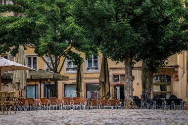 Strasbourg, Alsace, Fransa 'da geleneksel yarı ahşap evlerle çevrili bir şehir meydanındaki Alsatian şarap koçanı restoranlarında açık masa