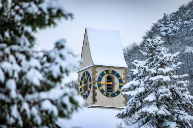 Winter wonderland in Stallikon, Switzerland, a picturesque view of a snow covered church tower amongst snowy trees after a fresh snowfall near Zurich clipart