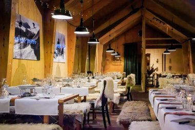 Zürih, İsviçre - 21 Kasım 2024: Kırsal Kış Harikalar Diyarı: Ahşap masalar, rahat kürk fırlatmalar ve fondü dağ evi restoranındaki şenlikli dokunuşlar