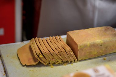 Bir blok kaz ciğeri, Fransa 'nın Strazburg kentindeki bir Noel Market köşkünde gurme sandviçler için bir şef tarafından kesiliyor.