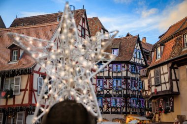 Fransa 'nın Colmar Noel Pazarı' ndaki bulanık yıldız Noel süsü. Arka planda süslemeli yarım ahşap çerçeveli evler var.