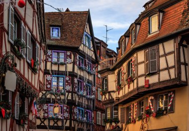 Fransa 'nın ünlü Colmar Noel Pazarı' nda kırmızı ve altın süslemeler ve oyuncak ayılarla süslenmiş geleneksel eski ahşap evler