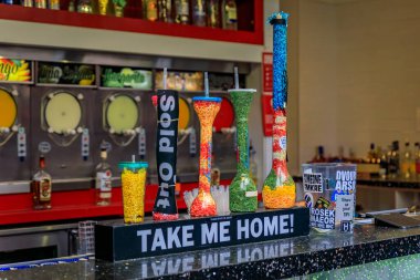 Las Vegas, Nevada, USA - October 24, 2021: Tall, colorful souvenir cups at a street bar, with frozen drink machines visible in the background clipart