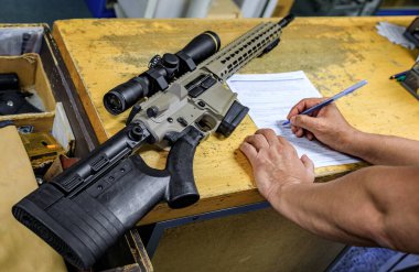 California gun shop: male buyer signs the paperwork beside a modern AR-15 rifle with a scope, verifying purchase in compliance with state regulations clipart