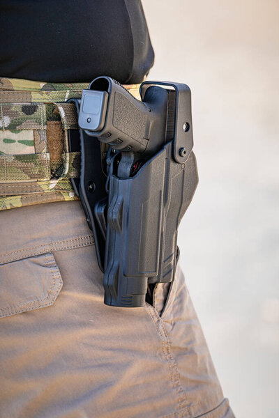 Камуфляжный тактический пояс с черной кобурой для пистолета и пистолетом, который носит стрелок для безопасного, доступного переноса для стрельбища, Калифорния