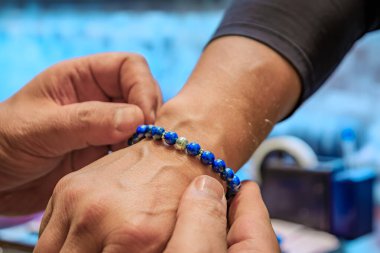 Bir kuyumcu, Türkiye 'nin İstanbul kentindeki Grand Bazaar' da bir erkek müşterinin koluna özel yapım lapis lazuli ve gümüş bilezik takıyor.