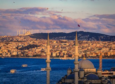 İstanbul, Türkiye 'de İstanbul' da Yeni Cami 'nin ön planında dramatik bulutların altında altın ışıkla yıkanan İstanbul Boğazı üzerindeki ikonik ufuk çizgisi