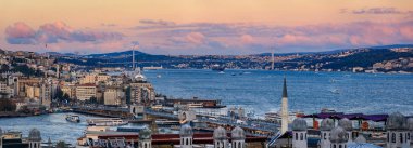 İstanbul, Türkiye 'nin ikonik şehir manzarası olan dramatik bulutlar altında altın saat günbatımında yıkanan Boğaz ve Köprü' nün panoramik manzarası