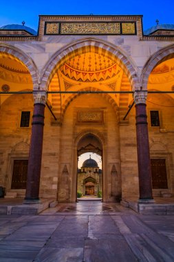 İstanbul, Türkiye 'de günbatımının yumuşak ışığıyla aydınlanan, huzur dolu bir iç kubbeye uzanan Süleyman Camii avlusunun kemerleri