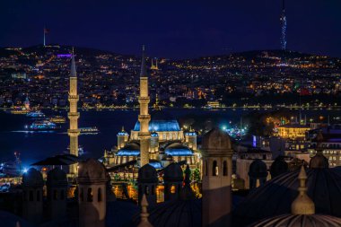 İstanbul, Türkiye 'de İstanbul' da Yeni Cami 'nin ön planında dramatik bulutların altında altın ışıkla yıkanan İstanbul Boğazı üzerindeki ikonik ufuk çizgisi
