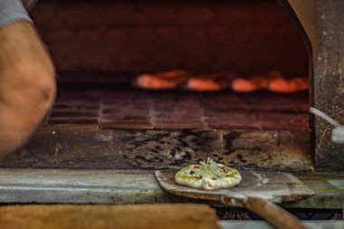 Köy taşından bir fırında pişirilmeye hazır ahşap bir kabuğun üzerinde, lezzetli malzemeli taze Türk pidesi, İstanbul ve Türkiye 'de geleneksel gıda hazırlığı