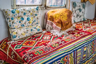 Geleneksel Türk divanı, Türkiye 'nin İstanbul kentindeki Grand Bazaar' da çiçek yastıkları, perde arkası atölye çalışmaları içeren canlı bir kilim desenli kumaşla kaplı