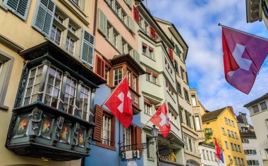 İsviçre 'nin ünlü Augustinergasse caddesi Zürih' teki Aldstadt 'taki geleneksel binaların tarihi cephelerinden İsviçre bayrakları sarkıyor.