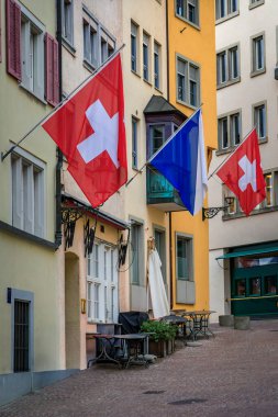 İsviçre 'nin ünlü Augustinergasse caddesi Zürih' teki Aldstadt 'taki geleneksel binaların tarihi cephelerinden İsviçre bayrakları sarkıyor.