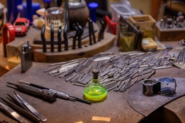 İsviçre, Zürih 'te özel metal işleme aletleri ve malzemelerle dolu bir kuyumcu tezgahı, metal matkap uçları ve bir şişe kuyumcu asidi.