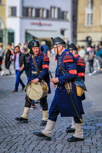 Zurich, Switzerland - April 12, 2024: Military dressed guild members perform at the historical Sechselauten celebrations near the Fraumunster church