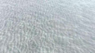 Kristal berrak tropik sahil sularının hava aracı görüntüsü dalgalanmalar ve su yansımaları sergiliyor.