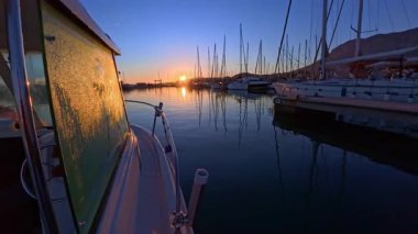 Tekne yan penceresinde çiğ taneleri marina rıhtımında güneşin doğuşunda ıslanıyor.