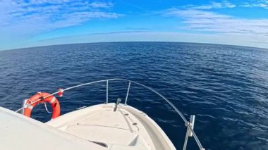 Bir yat açık, güneşli gökyüzüne bakan açık mavi okyanusta yelken açar.