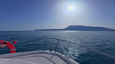 Bir yatın pruvası, açık denizde, açık denizde, berrak, güneşli bir gökyüzünün altında süzülüyor.